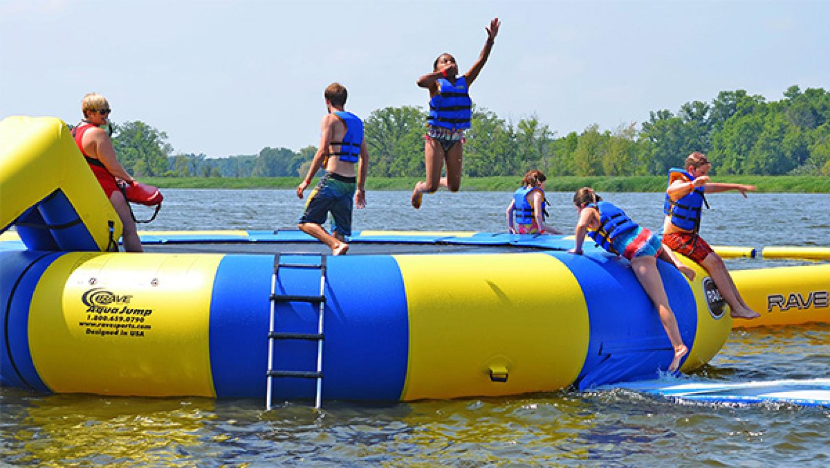 Campers jumping off water trampoline