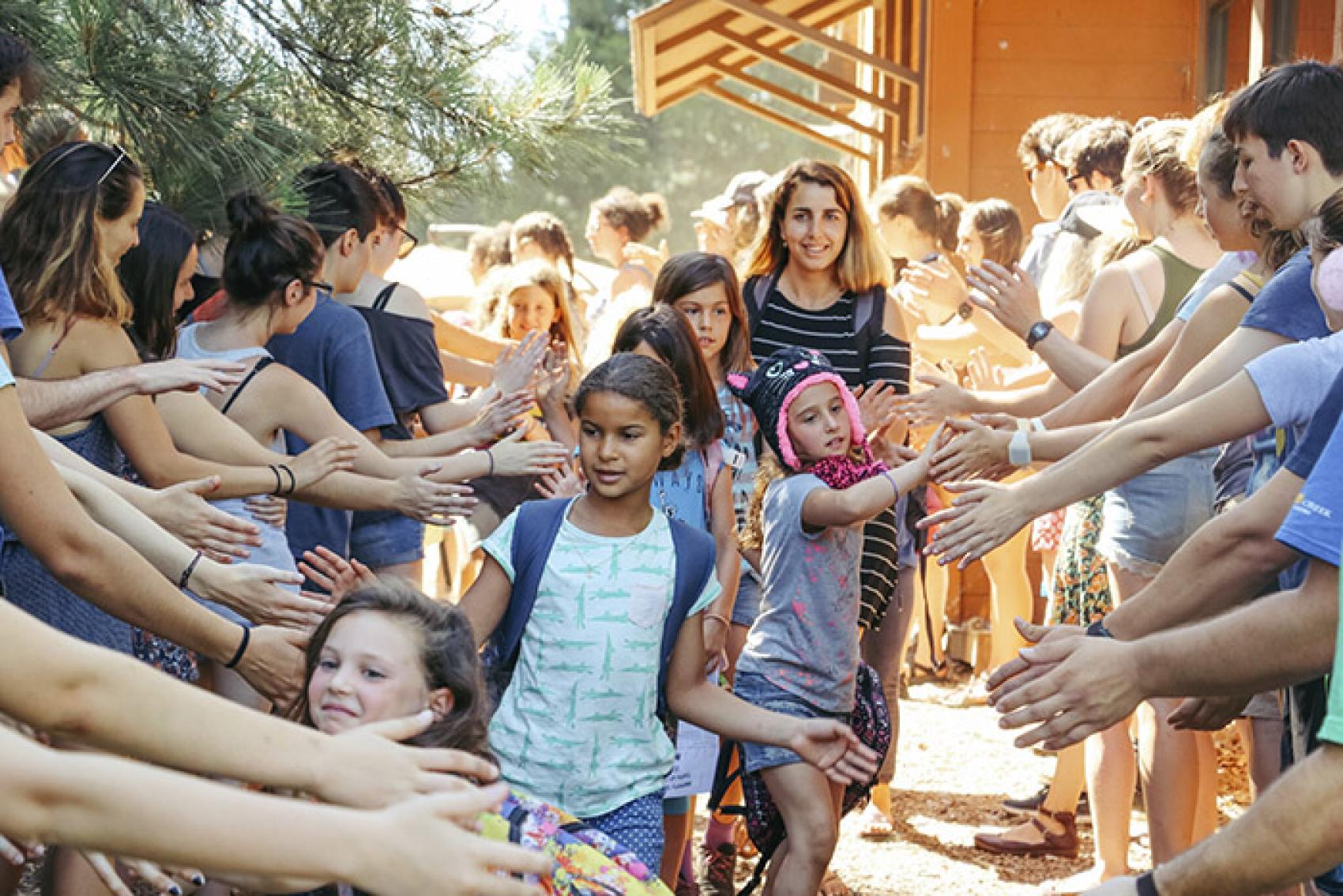 Campers in a line high-fiving staff and other campers