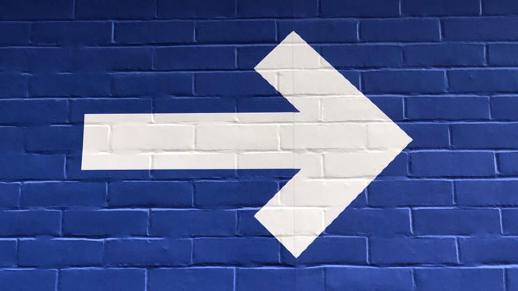 white arrow painted on blue wall