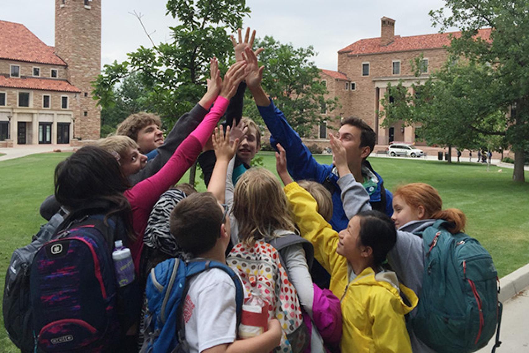 Campers and staff forming a high-five pyramid