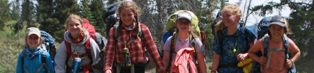 Line of campers in hiking gear walking in wooded area