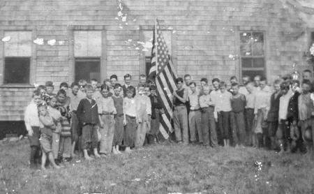 Boys standing next to American flag at Camp Rowley, 1915