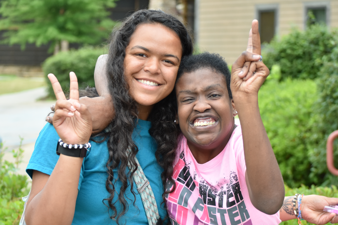 Counselor and camper smiling with peace sign hands