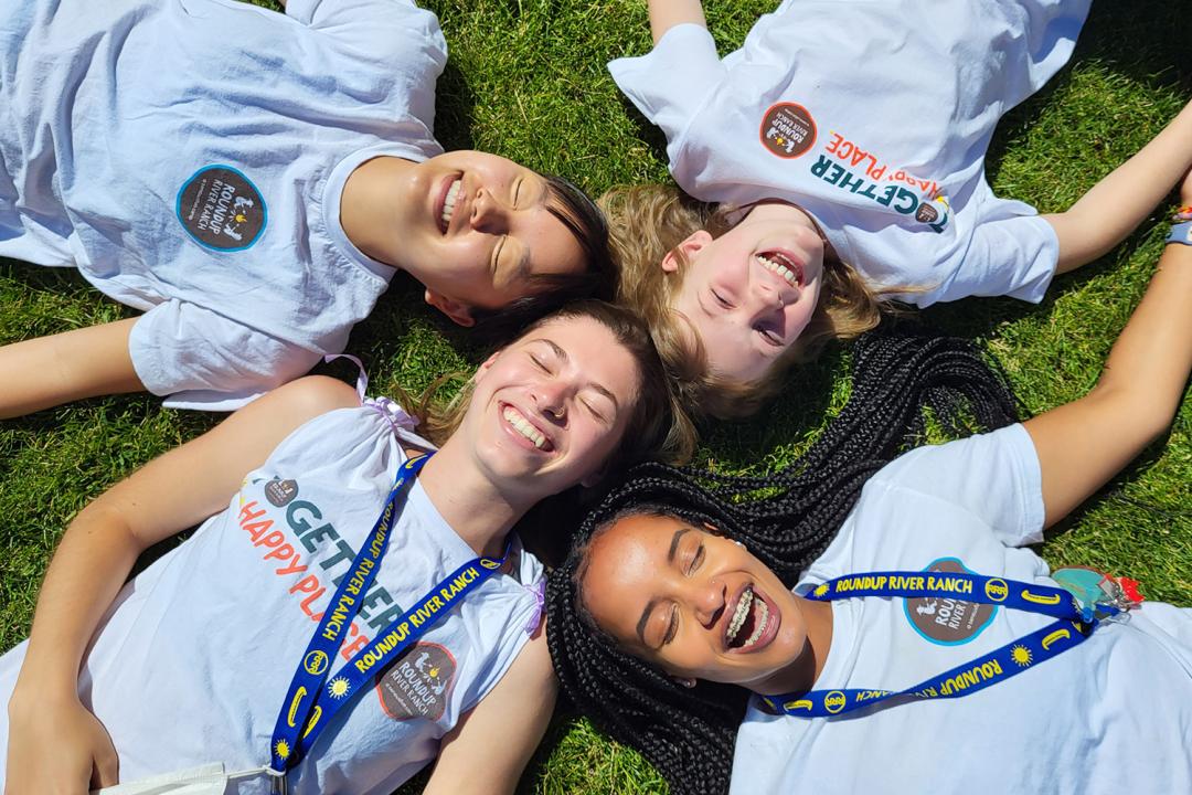 smiling camper friends laying on grass