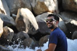 Camp Counselor sitting in front of river smiling with rocks in the background