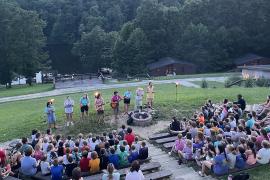 campers sitting on benches in front of a group of staff