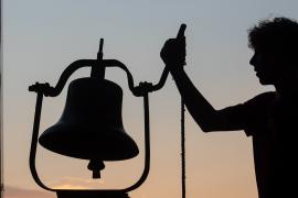 camp person ringing bell at dawn