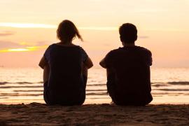 Friends sitting on beach at sunset