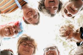 Circle of staff looking down and smiling at camera