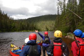 campers wearing helmets and flotation devices standing in front of a body of water