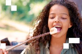 Young child eating marshmallow off stick