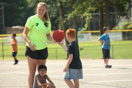 camper handing basketball to camp staff