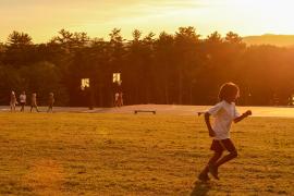 camper running on field with sun setting