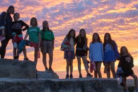 camp group in front of sunset