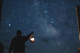 Person holding lantern with starry night sky