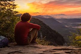 person sitting on rock watching sunset