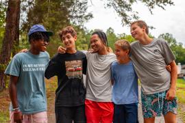 Five campers smiling at each other