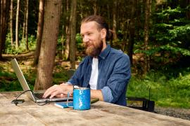 man working on laptop in wooded area