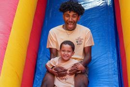 camp staff with camper on inflatable slide