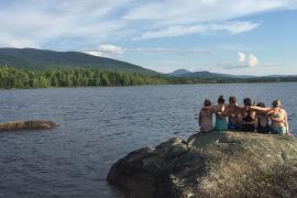 campers sitting on rock looking out over lake