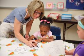 Staff helping camper with art worke