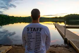staff member looking over lake at sunrise